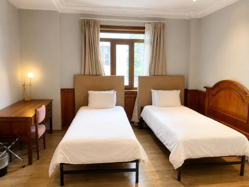 a room with two beds and a desk and a window at Cavi Rooms 304 in Cuenca
