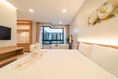 a bedroom with a large white bed and a television at Serene Pool Villa Pattaya 2 in Pattaya