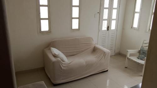 a white couch sitting in a room with windows at Jabutiana casas Mobiliadas in Aracaju