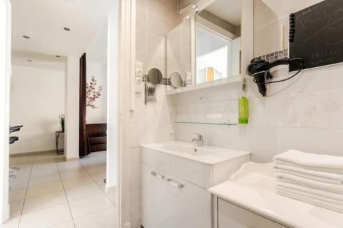 a white bathroom with a sink and a mirror at Au Moulin d'Or in Lille