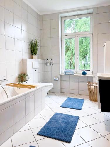 a bathroom with a tub and a sink and two blue rugs at Ferienwohnung Ostseeglück in der Villa Marie in Kühlungsborn