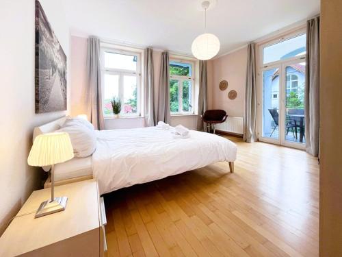 a bedroom with a large white bed and windows at Ferienwohnung Ostseeglück in der Villa Marie in Kühlungsborn