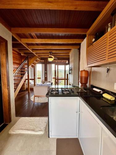 a kitchen with white cabinets and a living room at Chalé dos Manacás Duplex in Venda Nova do Imigrante