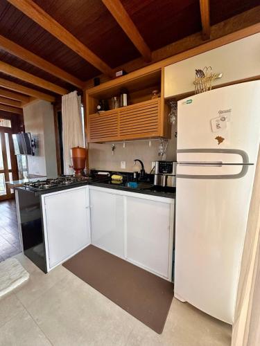 a kitchen with white cabinets and a white refrigerator at Chalé dos Manacás Duplex in Venda Nova do Imigrante