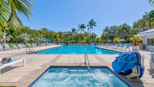 a pool at a resort with chairs and umbrellas at Keys Waterfront Condo with Beach Pool Sunset Views in Tavernier