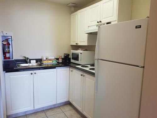 a kitchen with white cabinets and a white refrigerator at Travelodge by Wyndham Kamloops Mountview in Kamloops