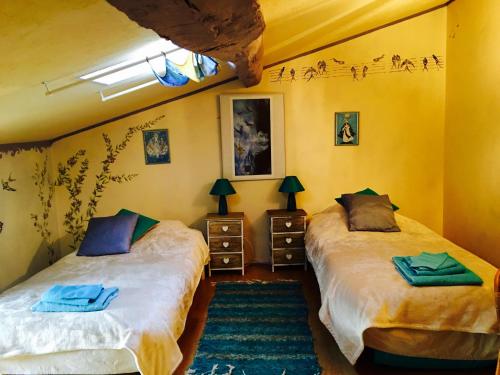 Dos camas en una habitación con paredes amarillas. en Occitania B&B, en Puivert