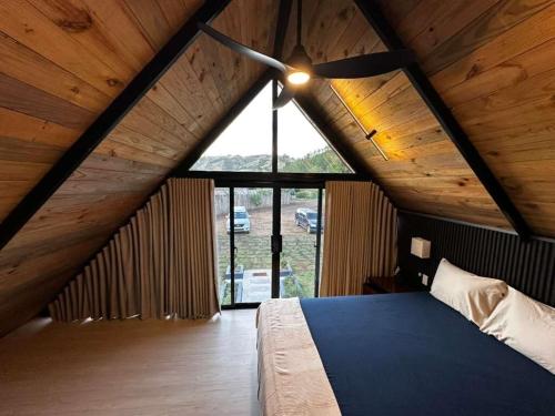 a attic bedroom with a bed and a large window at Alpine River Cabin with direct access to the river in Río Arriba