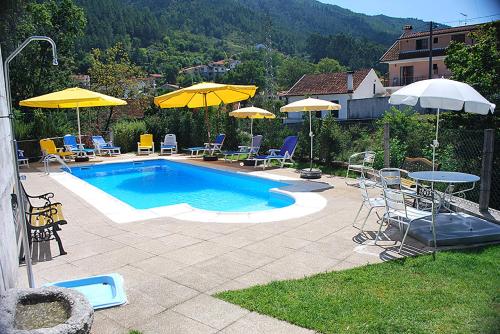 a pool with chairs and tables and umbrellas at Residência Iris in Geres