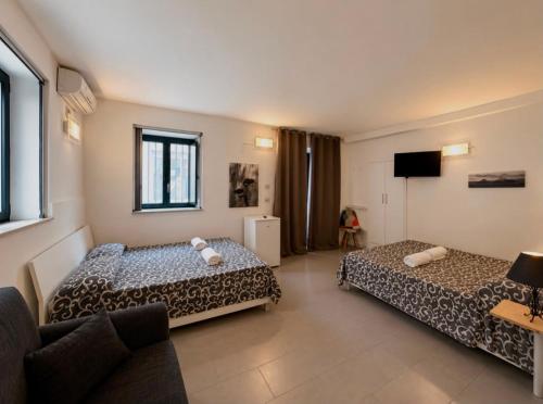 ein Hotelzimmer mit zwei Betten und einer Couch in der Unterkunft Sei ottavi in Gioiosa Marea