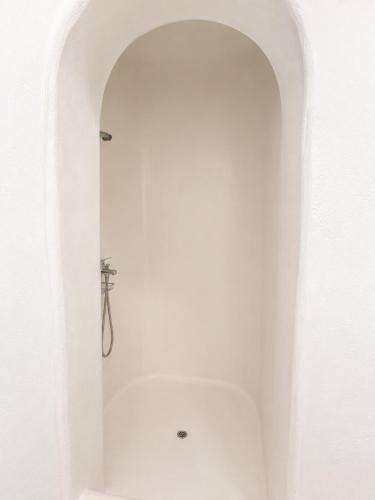 a bathroom with a shower in a white wall at Orama suite I in Mikonos