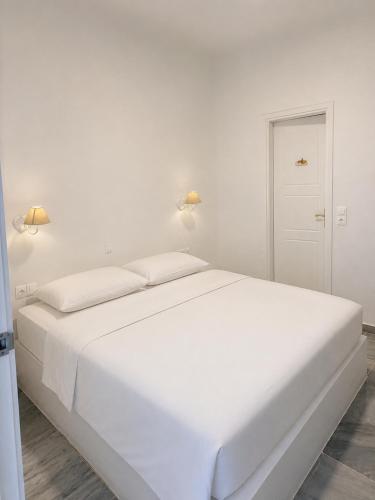 a white bed in a white bedroom with two lamps at Orama suite I in Mikonos