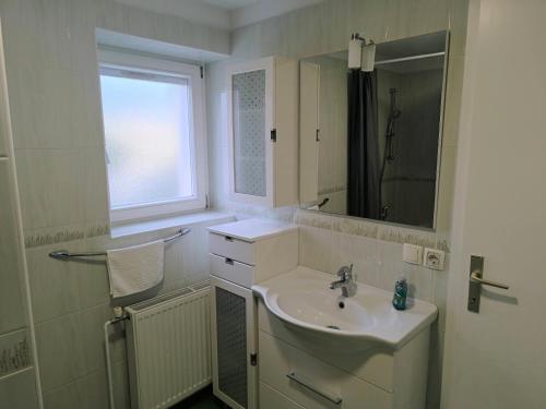 a white bathroom with a sink and a window at Apartment Maria Domžale in Domžale