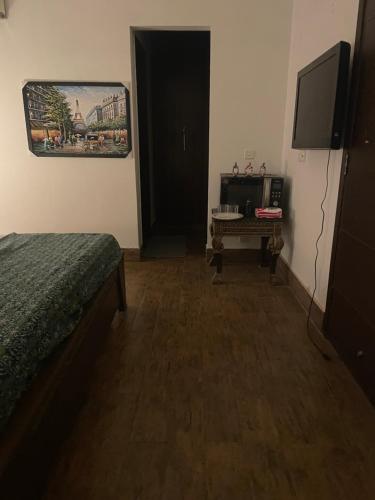 a bedroom with a bed and a television and a table at Executive Guest Room - Helcion Residency in Lahore