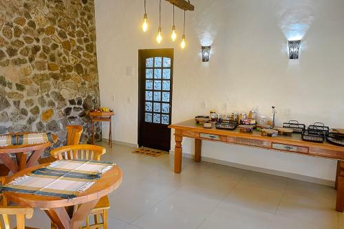 a room with a table and chairs and a stone wall at VELINN Pousada Canto da Cascata in Camanducaia