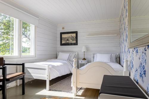 a white bedroom with two beds and a window at Villa Väderkulla in Porvoo
