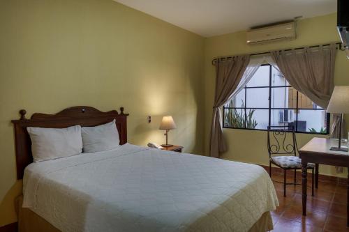 a bedroom with a bed and a window and a desk at Hotel Villa Terra in San Salvador
