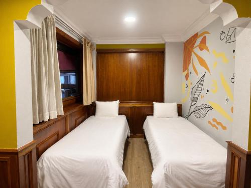 two beds in a small room with a window at Cavi Rooms 305 in Cuenca