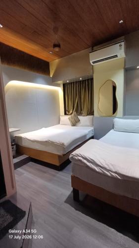 a hotel room with two beds and a window at Hotel Regal Plaza in Mumbai