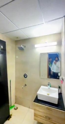 a bathroom with a white sink and a mirror at Omaxe Hazratganj Stay in Lucknow
