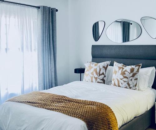 a bedroom with a bed with pillows and mirrors on the wall at The cozy garden suites in Sandton