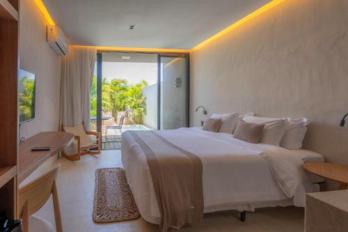 a bedroom with a large white bed and a balcony at Koloa Concept Hotel in Barra Grande