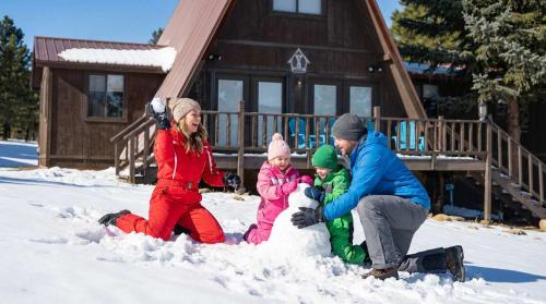 a man and a woman and two children playing in the snow at Rustic Mountain Getaway~Golf~Skiing~Hiking in Angel Fire
