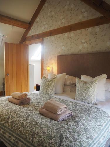 a bedroom with a large bed with towels on it at Hobbs Hole Cottage & Studio in Great Tew