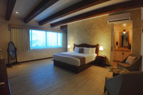 a bedroom with a bed and a chair in a room at Casa Barco Hotel Boutique in Isla Mujeres