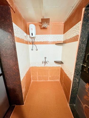 a small bathroom with an orange and white shower at Shree Kelbai Homestay in Malvan