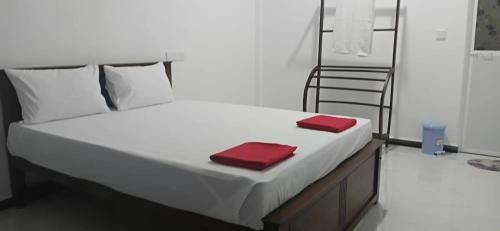 a white bed with two red towels on it at Sivas friendly guest house in Nilaveli