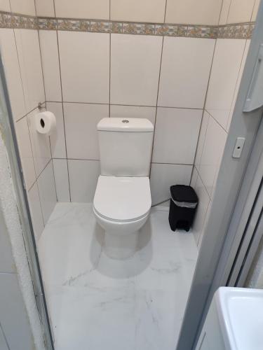 a white bathroom with a toilet and a trash can at Motel Hotel Le Premier in Venâncio Aires