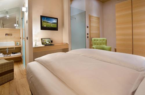 sypialnia z białym łóżkiem i zielonym krzesłem w obiekcie Hotel Larice w Livigno