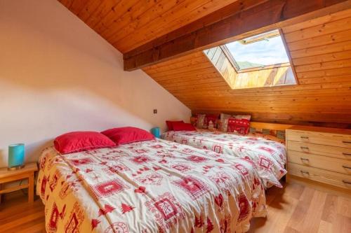 a bedroom with two beds with red pillows and a window at Les Balcons de St So Appartement A in Saint-Sorlin-dʼArves
