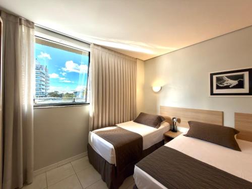 a hotel room with two beds and a window at Igaras Hotel - Centro de Otacílio Costa, 49km de Lages in Otacílio Costa