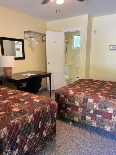 a hotel room with two beds and a desk at McGregor Inn Motel in Saratoga Springs