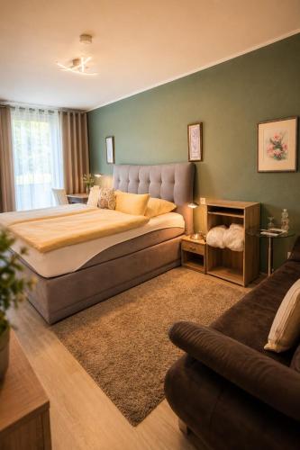 a bedroom with a large bed and a couch at WELLNESS Hotel UHLENBERG in Bad Münstereifel