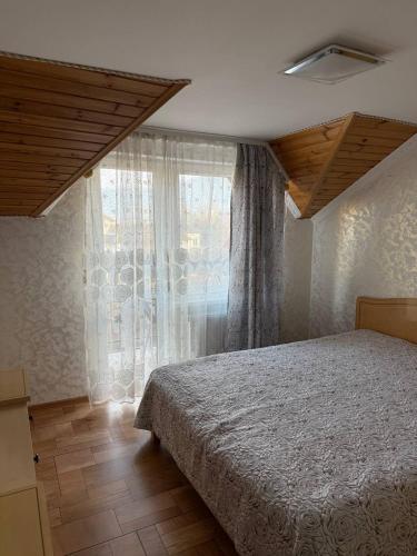 a bedroom with a bed and a large window at Колиска Карпат in Slavske