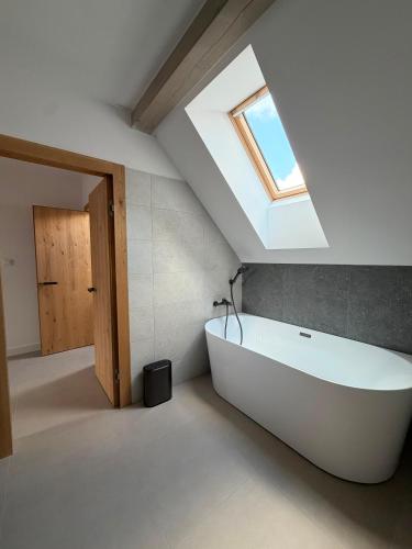 a white bath tub in a bathroom with a skylight at Apartmány Vysoké in Vysoké nad Jizerou