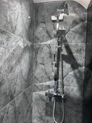 a shower in a bathroom with a stone wall at Double Room Private Bathroom Parking South Croydon in Addington