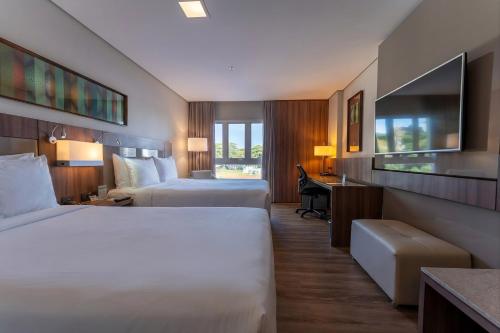 a hotel room with two beds and a desk at Deville Prime Campo Grande in Campo Grande