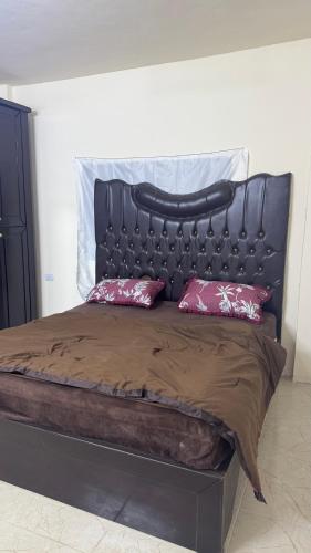 a large bed with a black headboard and two pillows at مطل محنا الجبلي in Ajloun