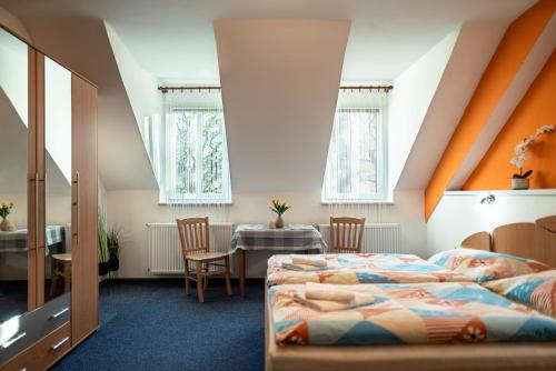 two beds in a room with a table and chairs at Pension Gábi in Františkovy Lázně