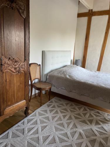 a bedroom with a bed and a wooden cabinet and a chair at Le balcon in Beaumont-le-Hareng