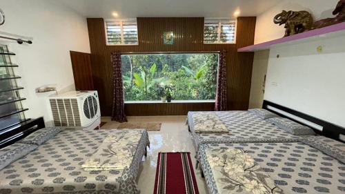 two beds in a room with a large window at Doddakallu Betta Homestay Coorg in Somvārpet