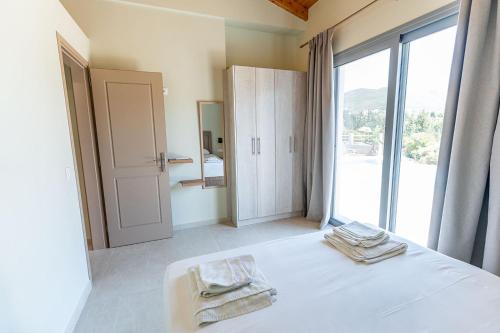 a bedroom with a bed and a large window at Tsoutsis Villas in Marantochori