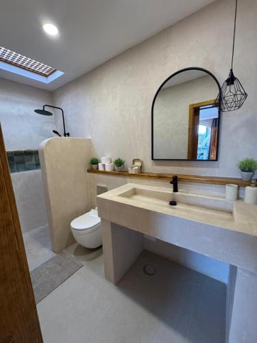 a bathroom with a sink and a toilet and a mirror at Villa Majora - Piscina climatizada in Tuineje