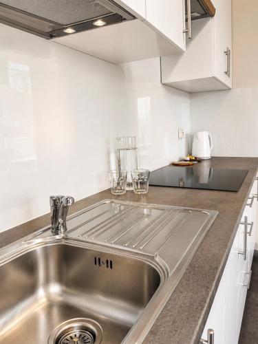 a stainless steel sink in a kitchen with white cabinets at Apartamenty ABRACADABRA in Ustroń