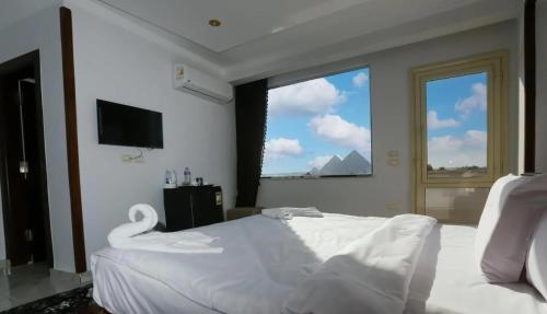 a bedroom with a white bed and a large window at Pyramids Giza inn in Cairo