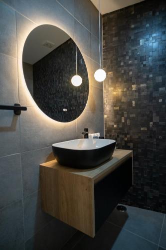 a bathroom with a black tub and a round mirror at Douro River Apartment in Vila Nova de Foz Coa